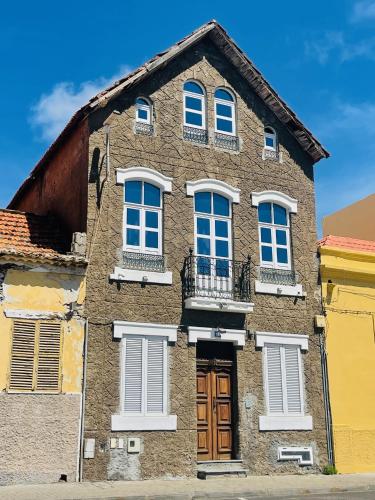 a brown brick building with white windows and a door at KAZARÃO DI MAVETE- Guesthouse in Praia