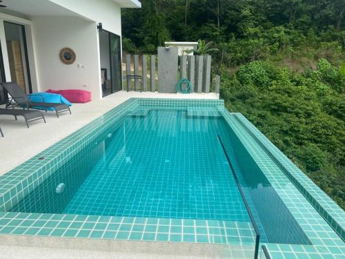 a swimming pool with blue tiles on the side of a house at Villa Staring at the sea 3/4 ch jacuzzi piscine in Koh Samui 
