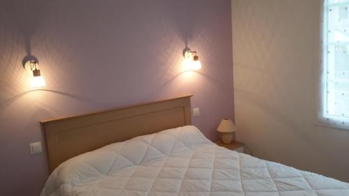 a bedroom with a bed with two lights on the wall at maison de l ile in Damgan