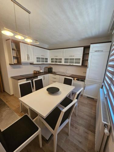 a kitchen with a table and chairs and white cabinets at Dardania-Home in Prizren