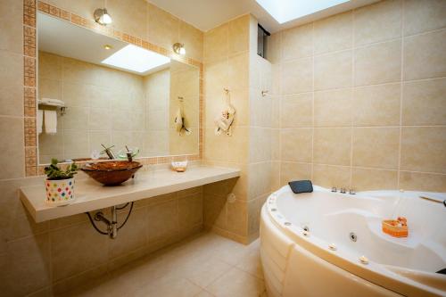 a bathroom with a tub and a sink and a mirror at Hotel Agustos Urubamba in Urubamba