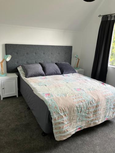 een slaapkamer met een groot bed met een grijs hoofdeinde bij Kiwi Hosts in Auckland