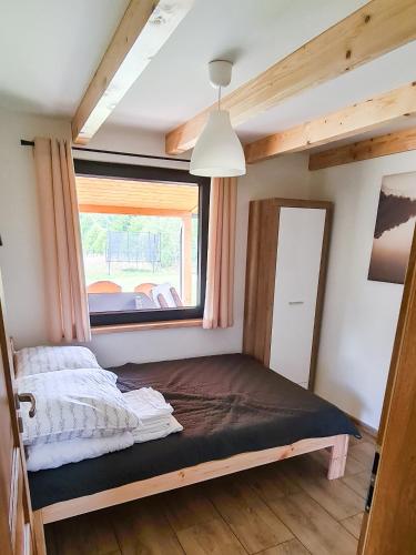 a bed in a small room with a window at Domek letniskowy Wigsun in Leszczewek
