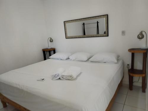 a bedroom with a white bed with a mirror on the wall at Hotel Casa Del Angel in Chetumal