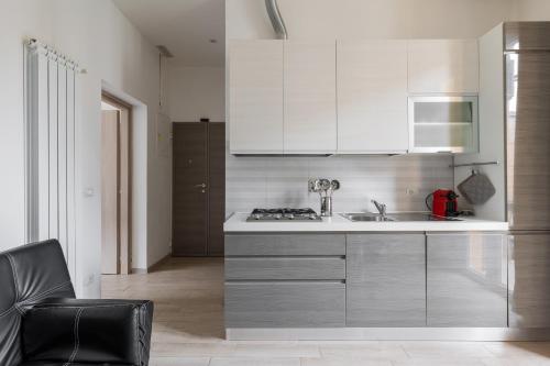 波隆那的住宿－博洛尼亞套房公寓，厨房配有白色橱柜、水槽和炉灶。