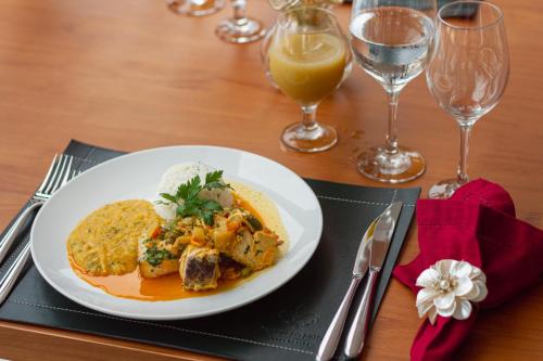 a plate of food on a table with glasses of wine at Principe do Mutá Hotel Design in Santa Cruz Cabrália