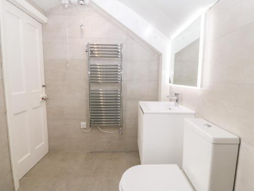 a white bathroom with a toilet and a shower at Tyddyn Serri in Rhosneigr