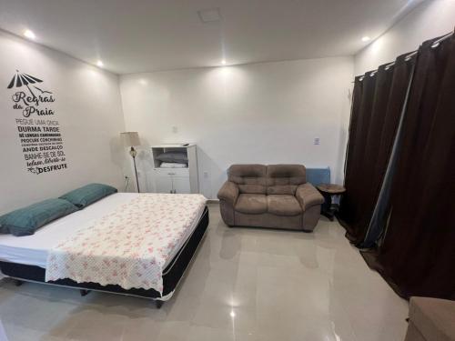 um quarto com uma cama, um sofá e uma cadeira em Pontal do Atalaia 28 em Arraial do Cabo