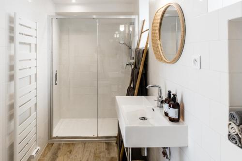 ein weißes Bad mit einer Dusche und einem Waschbecken in der Unterkunft Mer nature, appartement spacieux by Les Filles du Bord de Mer, petite terrasse vue mer in Port-en-Bessin-Huppain