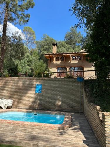 a house with a swimming pool in front of a house at Casa Rural Ermita Santa Maria de la Sierra in Arroyo Frio