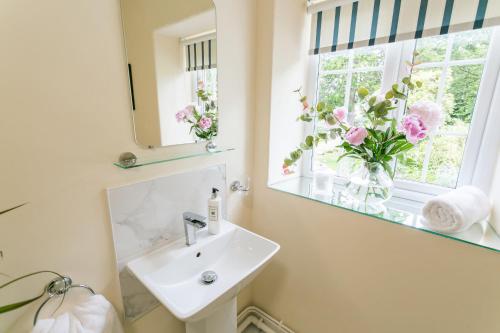 a bathroom with a sink and a window with flowers at Cae Mab Dafydd in Llanfairfechan