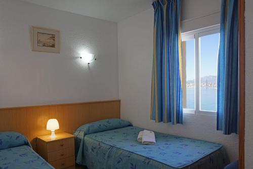 a hotel room with two beds and a window at Apartamentos Las Carabelas in Benidorm