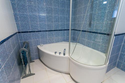baño de azulejos azules con bañera y aseo en Tal Y Bont Uchaf Cottage, en Bangor