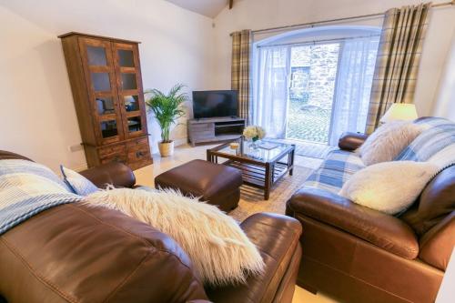 a living room with two leather couches and a television at Tal Y Bont Uchaf Cottage in Bangor