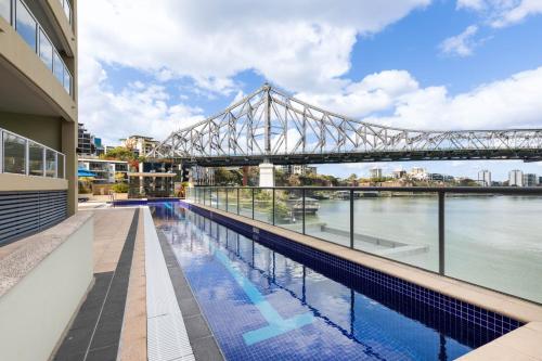 a bridge over a river with a swimming pool at River Place hosted by AAB in Brisbane