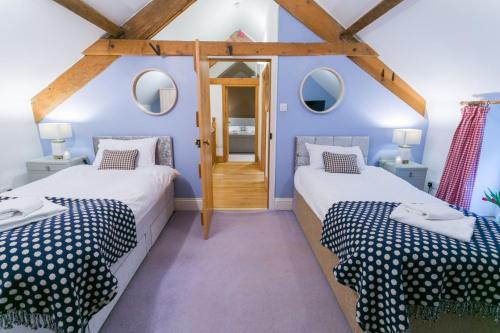 two beds in a room with blue walls and wooden beams at Tal Y Bont Uchaf Stables in Bangor