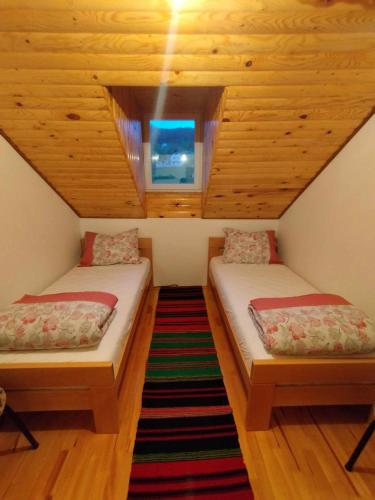 2 łóżka w pokoju na poddaszu z oknem w obiekcie Prenoćište Rubin 