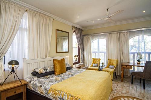 a bedroom with a bed and a desk and windows at La Loggia Bed and Breakfast in Durban