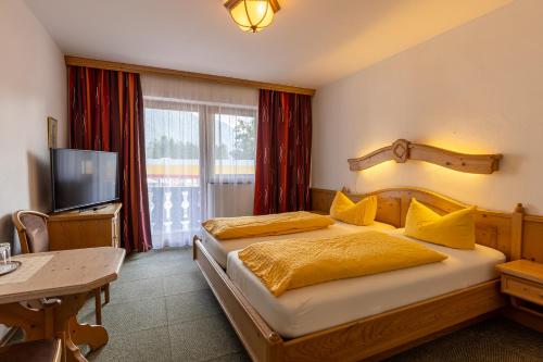 a bedroom with a bed with yellow pillows and a television at Hotel Alpenhof in Oberau