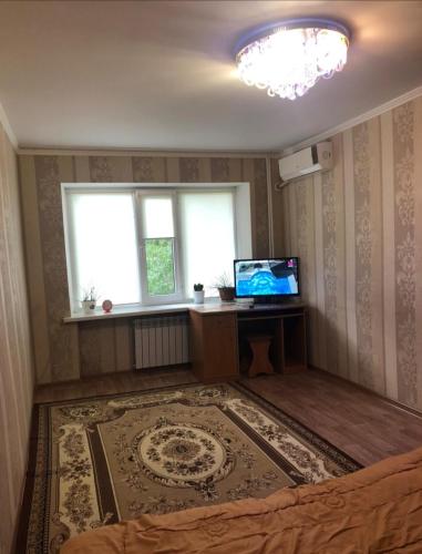 Habitación con cama, TV y ventana. en 1 комн. квартира на Есет батыра, en Aktobe