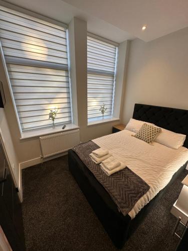 um quarto com uma cama grande e 2 janelas em Hamlet Court Apartments 1A em Southend-on-Sea