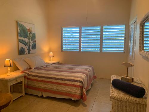 1 Schlafzimmer mit einem Bett und 2 Fenster mit Fensterläden in der Unterkunft Villa Belvedere - 5 minutes walk to the Beach in Dickenson Bay