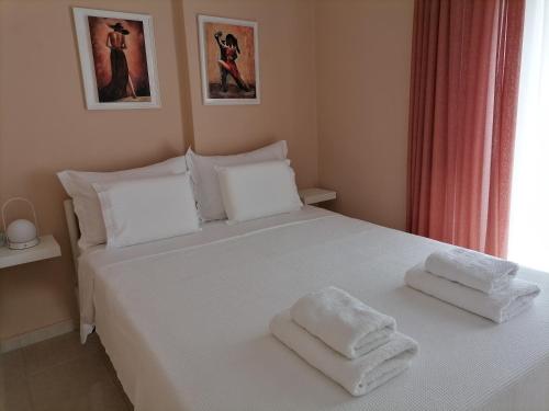 a bedroom with a white bed with towels on it at JOY's Central Apartment in Thessaloniki
