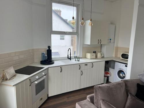 a kitchen with white cabinets and a window at Forte circle, luxury apartments in South Norwood