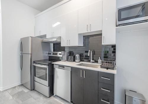 a kitchen with white cabinets and a stainless steel refrigerator at Luxurious 3BD Apt in heart of downtown 5 min walk to Bell Center in Montréal