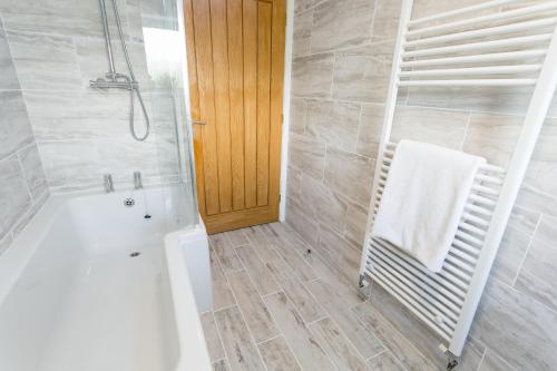 a bathroom with a tub and a shower with a towel at 10 Beach Road in Menai Bridge