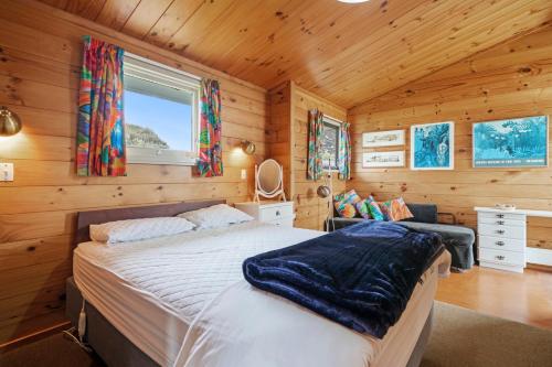 een slaapkamer met een bed in een houten hut bij The Beachsider - Te Horo Beach Holiday Home in Te Horo