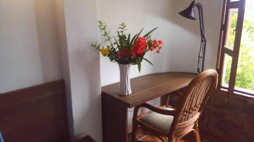 eine Vase mit Blumen auf einem Tisch mit zwei Stühlen in der Unterkunft Esperando solo por ti.. in Pampatar