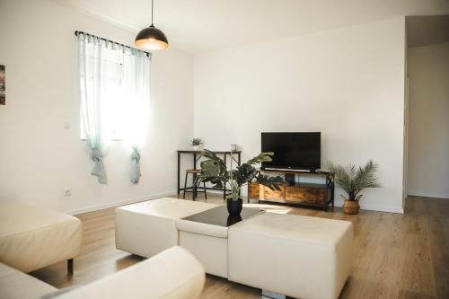 a living room with white furniture and a flat screen tv at Shine Apartment Wackersdorf I in Wackersdorf
