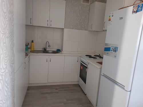 a kitchen with white cabinets and a white refrigerator at Эко дом in Astana