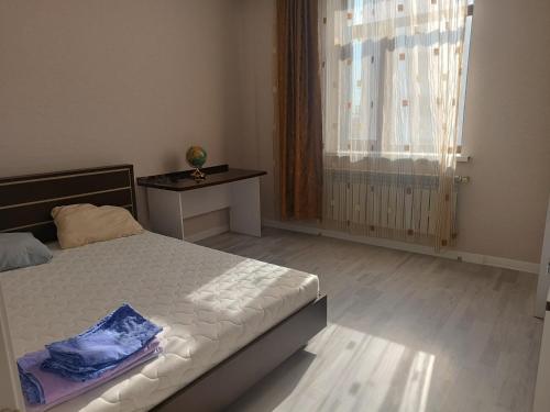 a bedroom with a bed and a table and a window at Эко дом in Astana