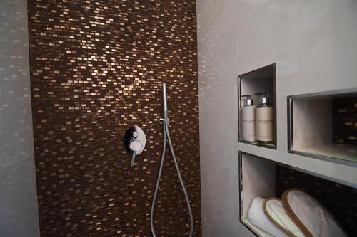 a shower in a bathroom with a brown tiled wall at Il Filo Di Arianna-Mola-Bed and Breakfast in Mola di Bari