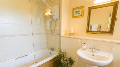 uma casa de banho com um lavatório, uma banheira e um espelho. em Beudy Odyn em Pentraeth