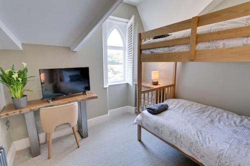 a bedroom with a bunk bed and a desk with a television at Eryl Mor in Menai Bridge