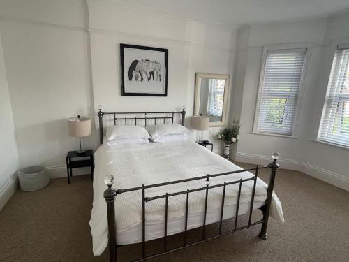 a bedroom with a bed with white sheets and two windows at 3 bed flat+parking- by beaches in Parkstone