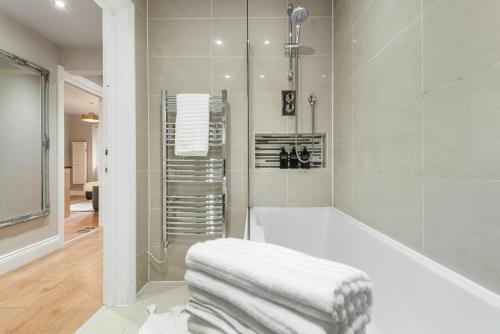 Central Whitechapel - Steps from Station & Sights! في لندن: حمام أبيض مع حوض استحمام ودش