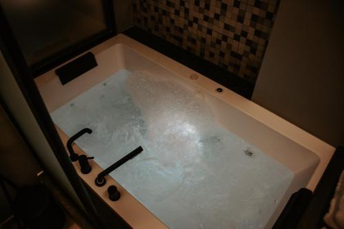 a bath tub filled with water in a bathroom at Dislocati BnB - Jacuzzi privata - Cucina - TV60" - Minimal Luxury in Marigliano