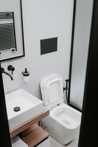 a bathroom with a white toilet and a sink at Dislocati BnB - Jacuzzi privata - Cucina - TV60" - Minimal Luxury in Marigliano