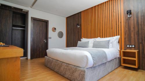 a bedroom with a large bed and a wooden wall at Razane Hôtel in Kenitra