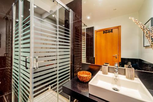 La salle de bains est pourvue d'un lavabo et d'une douche en verre. dans l'établissement Garajau Ocean Garden View, à Caniço