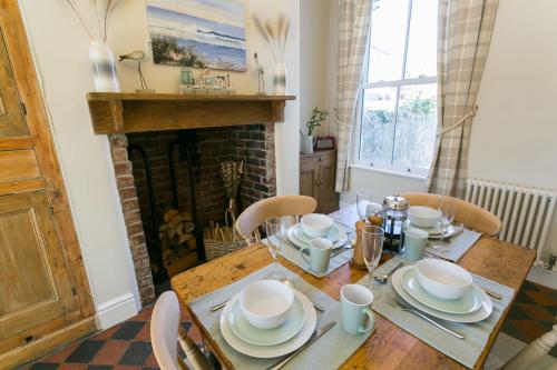 a dining room with a table and a fireplace at Glan Y Mor in Beaumaris