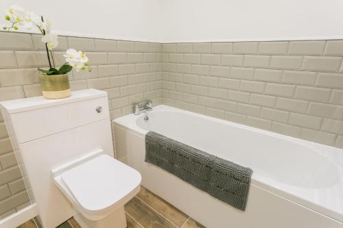 a white bathroom with a toilet and a bath tub at Gwel y Fenai in Penmon