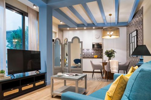 a living room with a blue couch and a tv at La Rosa de la Alfalfa in Seville