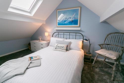 um quarto com uma cama branca e uma cadeira em Hyfrydle em Beaumaris