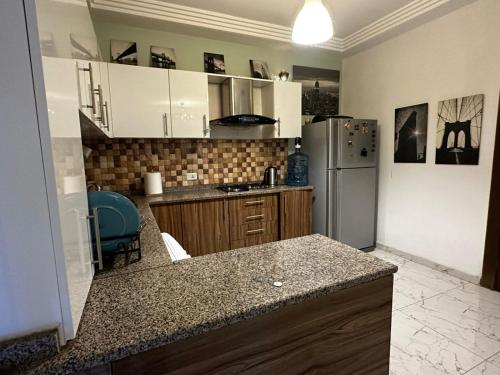 uma cozinha com armários brancos e um frigorífico de aço inoxidável em Abu alzoz home سكن مشترك em Amã
