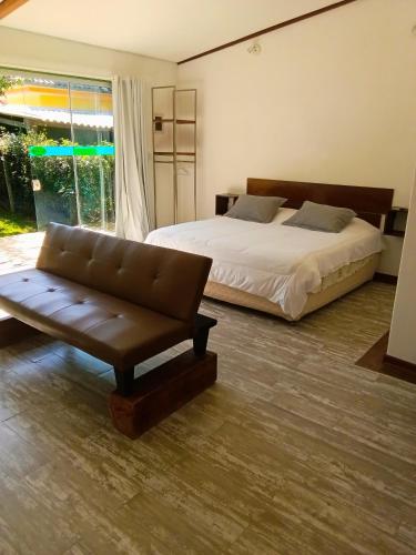 a bedroom with a bed and a couch and a window at Green Lodge Eco Life Hotel in Florianópolis